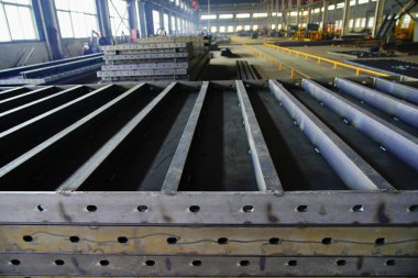 Çelik yapı atölyesindeki yay şekilli bileşenler ayrılmıştır ve kavisli çelik plakalar kubbeler ve kemerli köprüler gibi özel şekilli çelik yapıların çekirdek hammaddeleridir..