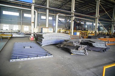 Çelik yapı atölyesindeki yay şekilli bileşenler ayrılmıştır ve kavisli çelik plakalar kubbeler ve kemerli köprüler gibi özel şekilli çelik yapıların çekirdek hammaddeleridir..