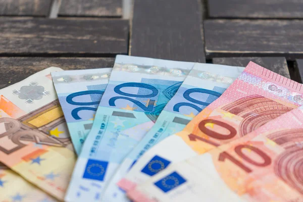 Pile of euro bank notes detail photo. Detail of ten, twenty and fifty euro bank notes on wooden background. Paper money on wooden background - Very soft focus.