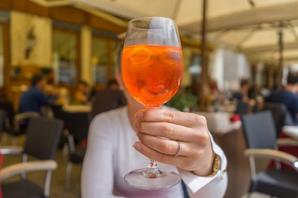 Aperol spritz o önünde holding arka plan üzerinde bulanık kadın
