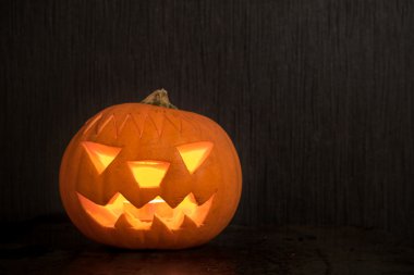 Cadılar Bayramı Balkabağı yansıması ile koyu zemin üzerinde parlayan yangın mum ile. Ürpertici yüz Halloween kabak - Önden Görünüm.