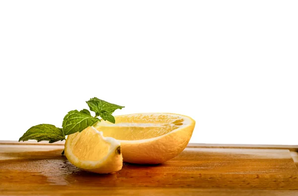 Un par de rodajas de limón rebanadas con una hoja de menta fresca en la mesa aislada — Foto de Stock