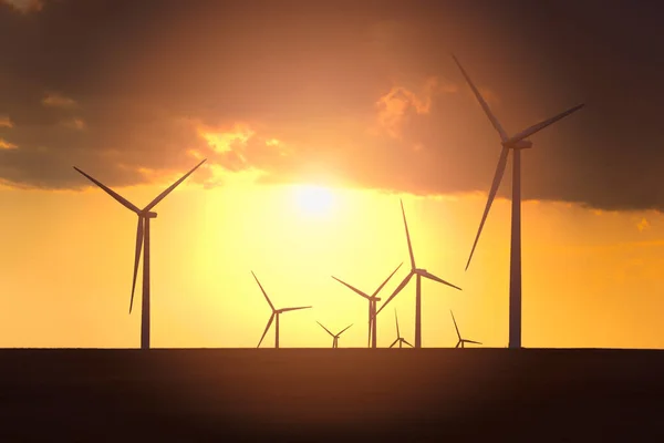 Giant electric windmills spin under a deep orange sky creating electricity on the eastern plains in Colorado.