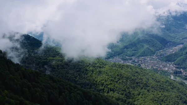 Fly through the green hills on a drone with a view of the city