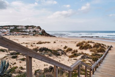 Monte Clerigo plajına giden merdivenler, arka planda köy var. Aljezur, Algarve Portekiz.
