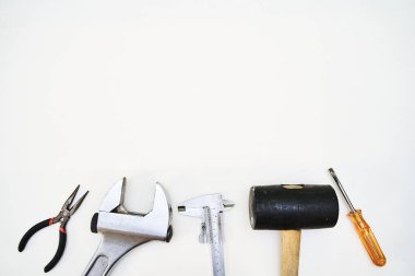 Plastik çekiç, pense, anahtar, tornavida ve beyaz arka planda metin için kopyalama alanı olan kalibre içeren kendin yap el aletleri grubu.