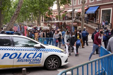 MADRID, SPAIN - 09 Mayıs 2021: Alarm sona erdikten sonra 9 Mayıs 2021 'de bir grup insanla Madrid' deki bir pazar kapısında polis arabası.