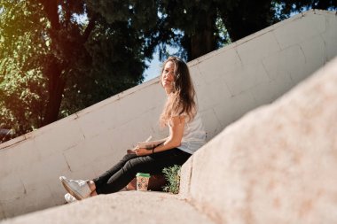 Kameraya bakarken elinde not defteriyle merdivenlerde oturan bir kadın. yaşam tarzı konsepti.