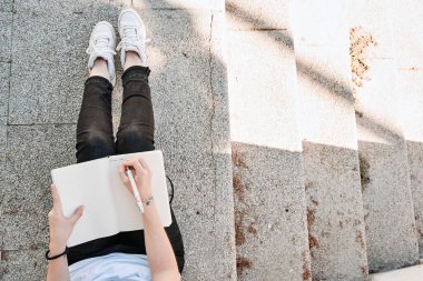 Merdivenlerde kitap okuyan bir kızın üst görüntüsü, fotokopi alanı olan.