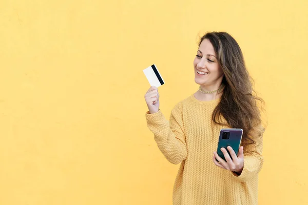 Tertawa Wanita Muda Menggunakan Ponsel Dengan Kartu Kredit Bank Tangan — Stok Foto