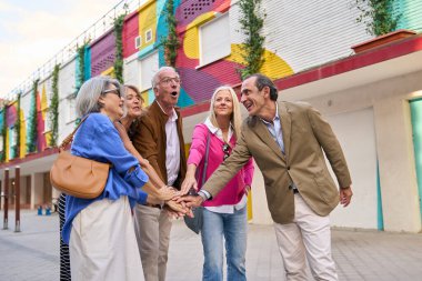 Mutlu kıdemli arkadaşlar açık havada el ele tutuşuyor, takım ruhunu, dostluğu ve başarıyı simgeliyor.
