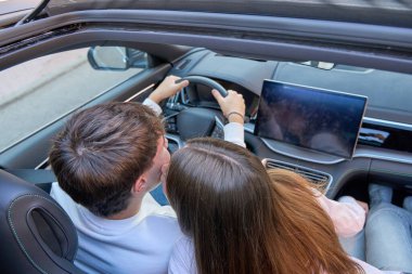 Çift samimi bir anı paylaşıyor, modern üstü açık bir arabanın içinde öpüşüyor, aşkı, aşkı ve seyahat macerasını simgeliyor.