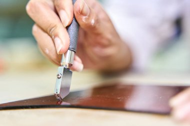 Sanatçı veya jöleli dikkatli bir şekilde bir atölyede cam kesici ile koyu cam çarşaf çizerek hassasiyet odaklı