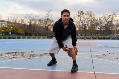 Sokak sahasında basketbol oynayan genç bir adam şehir sporu ve sağlıklı yaşam tarzı için hamleler yapıyor.