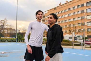 Şehir basketbol sahasında gülümseyen ve kaynaşan iki farklı arkadaş takım çalışmasını, sporu ve sağlıklı bir yaşam tarzını temsil ediyor.
