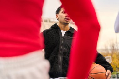 Top tutan erkek basketbolcu, takım arkadaşlarıyla şehir kortunda oyun stratejisine odaklanıyor.