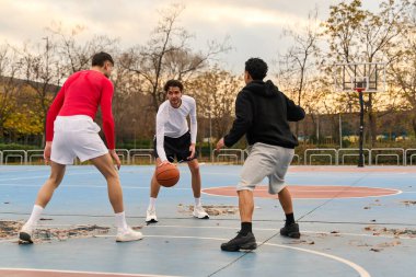 Açık havada basketbol oynayan üç sıradan adam var. Gün batımında salyalarını akıtarak sahada hareket ediyorlar.