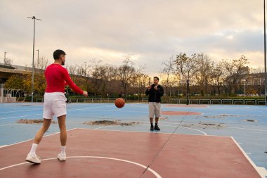 Açık havada basketbol oynayarak eğlenen iki adam. Kentsel bir ortamda eylem, spor ve pozitif enerji yakalamak