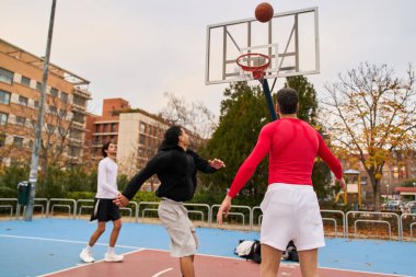 Açık şehir sahasında basketbol oynayan gençler takım çalışmasına ve gençlik yaşam tarzına odaklanıyorlar.