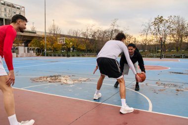Spor ve kentsel yaşam tarzını seven arkadaşlar, renkli bir sahada açık hava maçı sırasında top sürmek.