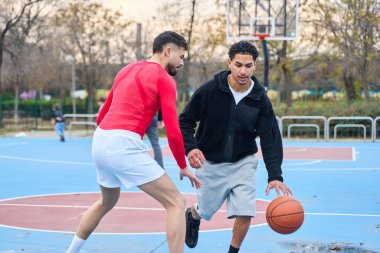İki genç adam mavi ve kırmızı bir sahada toplarını sallıyor, spor ve yarışmaya katılıyorlar.
