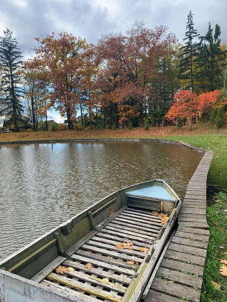 Ağaçlarla çevrili bir teknenin dikey çekimi ve parkta sonbahar yaprakları.