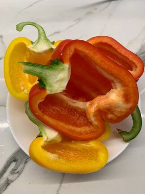 Taze dolmalık biber beyaz tabakta ikiye bölünmüş.