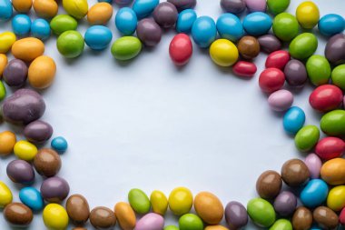 Beyaz bir masada renkli şekerler. Mutlu Paskalyalar. Üst Manzara. Düz dizayn. Tebrik için çerçeve