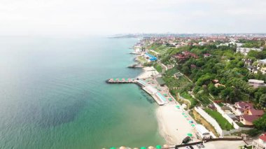 Odessa sahil şeridi, şemsiyeli şehir plajı, yeşil alanlar ve yerleşim alanları. Pürüzsüz sinemalar şehri, doğayı ve deniz kenarındaki uyumu yakalıyor..