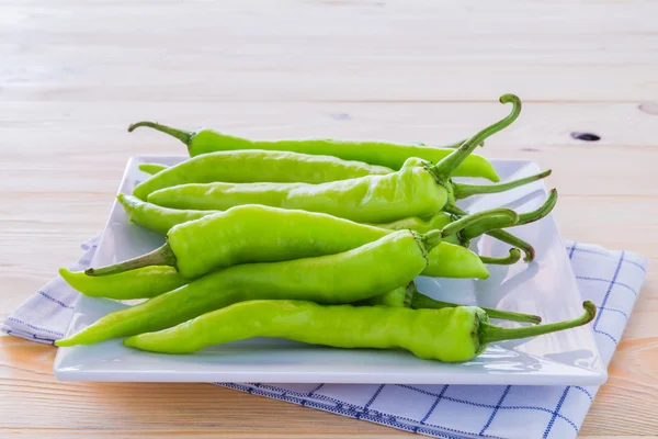 Poivrons verts sur une assiette et planchers de bois . — Photo