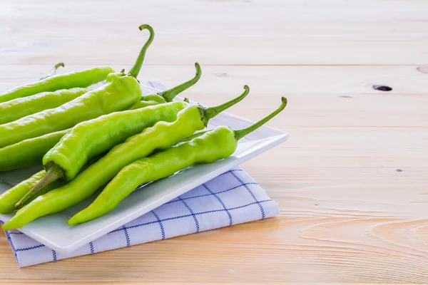 Poivrons verts sur une assiette et planchers de bois . — Photo