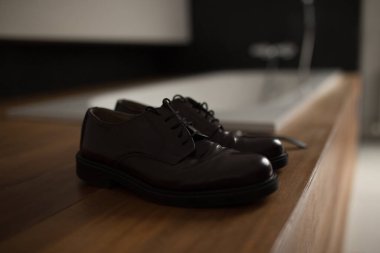 Koyu kahverengi deri ayakkabılar ahşap bir kaidede, yakın plan..