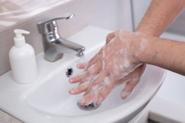 Musluğun altında akan suyla elleri sabunla yıkamak