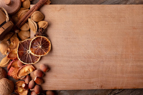 Wooden board with dried fruits and nuts. Brown and orange shades. Wide field for notes.