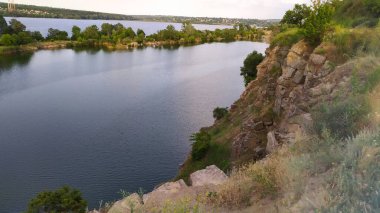 Kayaların ve köknar ağaçlarının arka planında göl var. Kanyon. İlkbaharın doğası, yaz. Metin ve tasarım için yer. Suyla dolu eski bir endüstriyel granit ocağının manzarası..