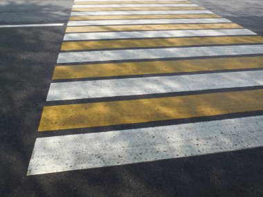Yol işaretleri, Zebra geçidi, yaya geçidi. Asfaltta geniş beyaz ve sarı çizgiler var..