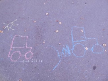 Asfalta renkli boya kalemleriyle çocuk resimleri: güneş ve iki traktör..