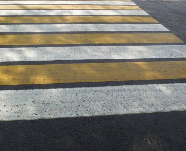 Yol işaretleri, Zebra geçidi, yaya geçidi. Asfaltta geniş beyaz ve sarı çizgiler var..