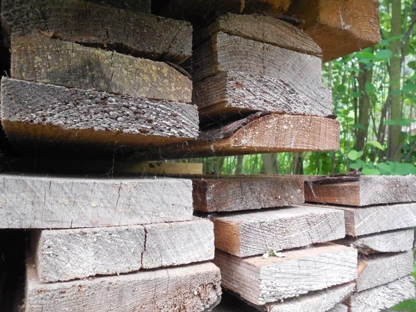 Old planks (lumber) are stacked in the garden.