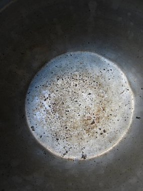 Eski bir alüminyum tencerenin dibinde korozyon, çizikler ve diğer hasarlar var. Fotoğraf gökyüzündeki dolunay görüntüsüne benziyor..