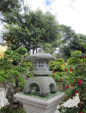 Vietnam, Ekim 2016. Güneydoğu Asya ülkeleri için geleneksel bir fener olan taş fener, Budist tapınak kompleksinin bahçesini süslüyor.