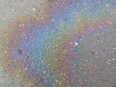 Asfaltta güzel, parlak, renkli bir benzin lekesi (otomobil yakıtı)..