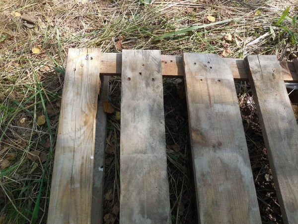 Eski, yarı çürümüş ahşap bir palet inşaat malzemeleri ve diğer malzemeleri taşımak ve depolamak için çimlerin üzerinde yatıyor..