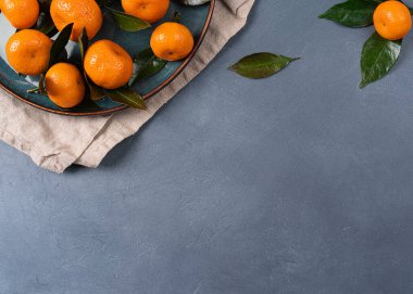 Taze mandalina portakalları ya da mandalinalar. Gri bir masanın üzerinde, tasarım ya da metnin için kopyalama alanı olan yapraklar.