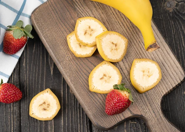 Ready to eat sliced bananas on a wooden desk, prepare for cooking desert or healthy food in a kitchen, top view macro