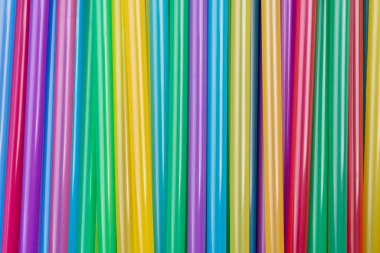 Karmaşık renkli plastik pipetlerin üst görüntüsü. Renkli pipetlerin olduğu arka planlara yakın, çevreyi korumak için plastik pipetleri yasaklıyor. Kokteyl tüpleri karışık renk arkaplanı