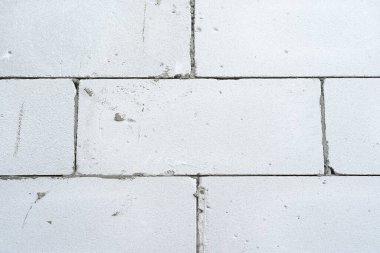 Duvarın önü farklı boyutlarda eski tuğlalardan yapılmış tuğlalar havan mermisiyle bağlanmış ve eski beyaz boyayla kaplanmış boyanın dokusu, arka planı aşınmış.