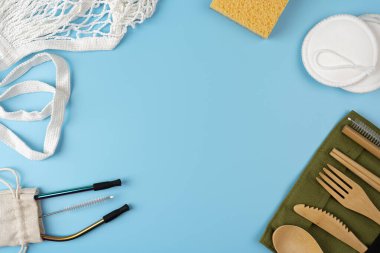 Bambu çatal bıçaklı çevre çantaları, yeniden kullanılabilir pamuk yastıklar ve mavi arka planda metal pipetler. Sürdürülebilir yaşam tarzı. Sıfır atık ve plastiksiz kavram.