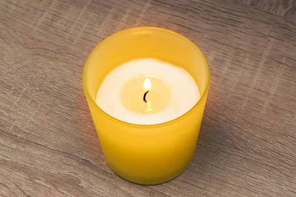 The candle burns in a yellow glass. Fragrant candles, gentle warm fire — Stock Photo, Image