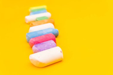 Çocuklar sarı arka planda bir sırada boya kalemleri çiziyor. Çok renkli tebeşir yakın plan..